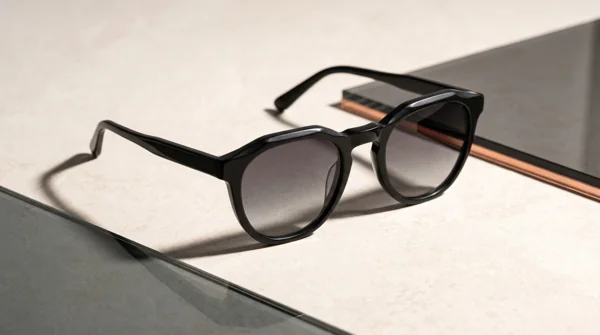 Sculptural black sunglasses on mineral and smoked glass